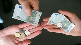 Zwei Personen halten Kleingeld und Fünf-Euro-Scheine in den Händen.
