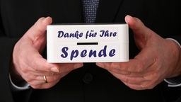 Nahaufnahme von Martin Wulffs Händen, Geschäftsführer Deutscher Spendenrat e.V., welcher eine Spendendose in den Händen hält.