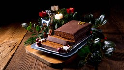 Aufgeschnittener Lebkuchen liegt auf einem Tablet, umgeben von einem Adventskranz
