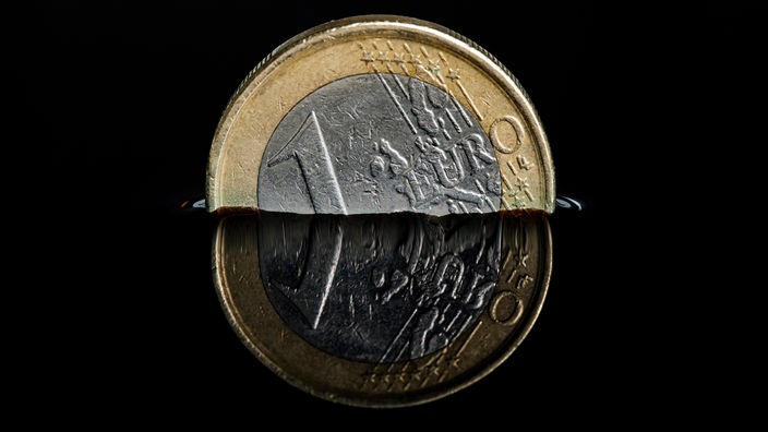 Ein Ein-Euro-Stück verschwindet in schwarzem Hintergrund