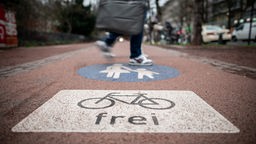 Gehweg mit Fahrrad- und Fußgängersymbol in Düsseldorf, den ein Fußgänger überquert