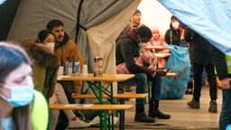 Flüchtlinge warten in einem Zelt am Kölner Hauptbahnhof, das als Anlaufstelle für sie dient. 