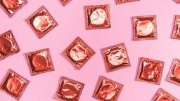 Verpackte Kondome auf rosa Hintergrund