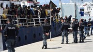 Migranten gehen im sizilianischen Hafen von Catania von Bord eines Schiffes.