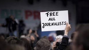 Schild mit der Aufschrift "Free all journalists" auf einer Veranstaltung