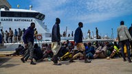Migranten aus Afrika im Hafen von Sfax, Tunesien, vor einem Schiff der "Garde Nationale". 
