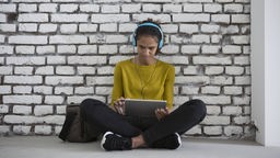 Eine Frau sitzt mit Kopfhörern vor einem Laptop