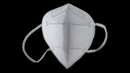 Eine weiße FFP-2-Maske vor schwarzem Hintergrund