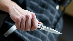 Ein junger Mann hält ein Messer in der Hand