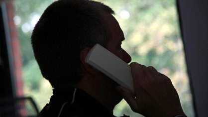 Person hält Telefonhörer ans Ohr