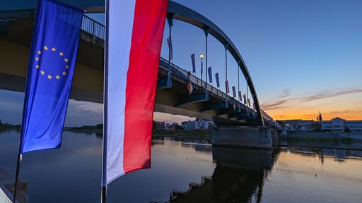 : Die Fahne der Europäischen Union und die Nationalflagge Polens wehen im Wind vor der Stadtbrücke über den Grenzfluss Oder zwischen Frankfurt (Oder) und dem polnischen Slubice. 