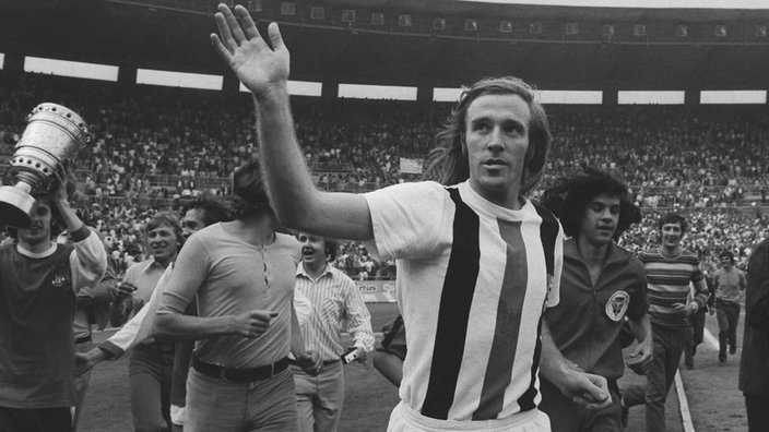 Günter Netzer läuft nach Ende des DFB-Pokalfinales 1973 die Ehrenrunde, winkt, links ist der Pokal zu sehen.