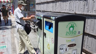 Ein Mann wirft Abfall in einen öffentlichen Müllcontainer in Kyoto, Japan. 