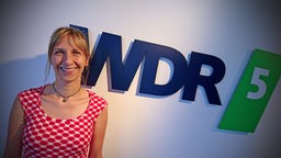 Sarah Hakenberg posiert vor dem WDR 5 Logo