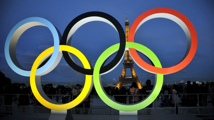 Die fünf olympischen Ringe, im Hintergrund ist der Eiffeltum zu sehen.