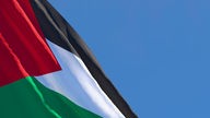 Eine palästinensische Flagge vor blauem Himmel.