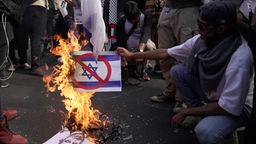 Teilnehmer einer antiisraelischen Demonstration verbrennt Israels Flagge und ein Plakat des israelischen Premierministers Benjamin Netanjahu.