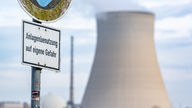 Ein Schild mit der Aufschrift "Anlagenbenutzung auf eigene Gefahr" steht vor dem Kühlturm des Atomkraftwerks (AKW) Isar 2. 
