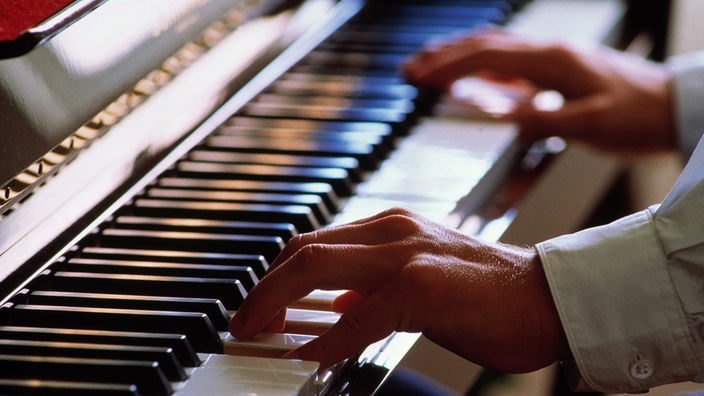 Symbolbild: Ein Pianist spielt Klavier, Detailaufnahme mit Blick auf die Hände.