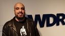 Abdelkarim steht vor dem WDR5-Logo