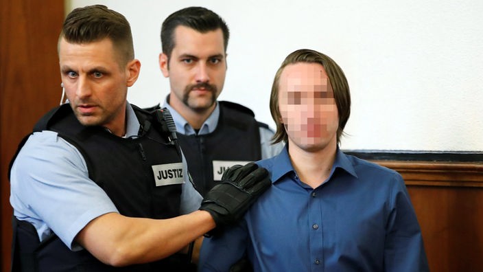 Der Angeklagte Sergej W. wird von zwei Polizisten in den Gerichtssaal gebracht.