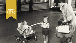 Eine Frau mit ihren zwei Kleinkindern an einem Bahnhof