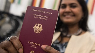 Der Deutsche Reisepass, mit beiden Händen hochgehalten