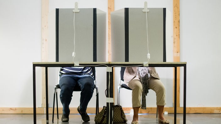 Zwei Bürger wählen hinter einer Wahlkabine