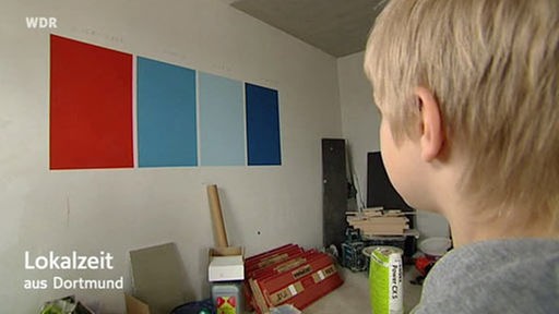 Ein Kind betrachtet Farbmuster an einer Wand