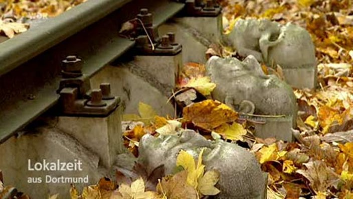 Bahngleise mit Skulpturen von Köpfen zum Gedenken an die KZ- Opfer