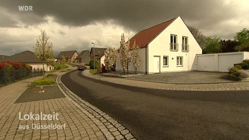 Dorfstraße mit Häuschen vor düsterem Himmel