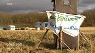 Das aufgeschlagene Lager der Tagebaugegner und ein Banner mit der Aufschrift: "Aufbäumen für Wald und Klima"