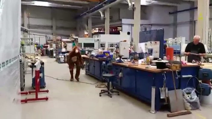 EIn Mann in einem Affenkostüm läuft durch eine Werkshalle.
