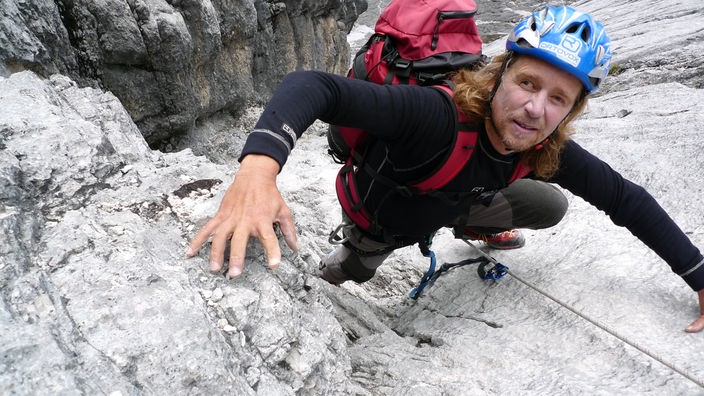 Andy Holzer beim Klettern in einer Wand.