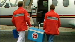 Sanitäter tragen eine Box zu einem Flugzeug