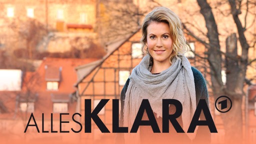 Eine junge Frau steht in dörflicher Kulisse, auf dem Bild der Schriftzug "Alles Klara"