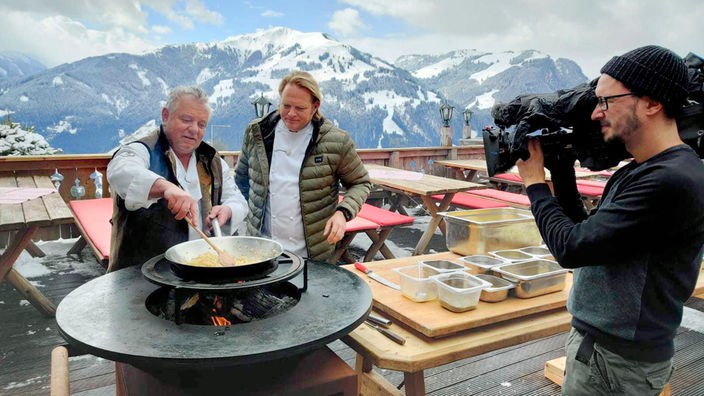 Vor dem Panorama der österreichischen Alpen kochen Fridel Schipflinger und Björn Freitag  deftige „Kaspressknödel“. 