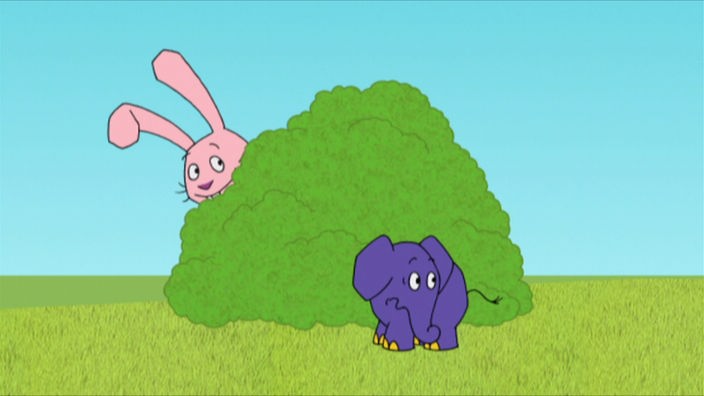 Elefant ist vor einem Gebüsch. Hinter dem Gebüsch versteckt sich Hase.