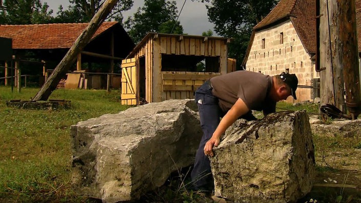 Ein Mann zwischen zwei sehr schweren, großen Steinen