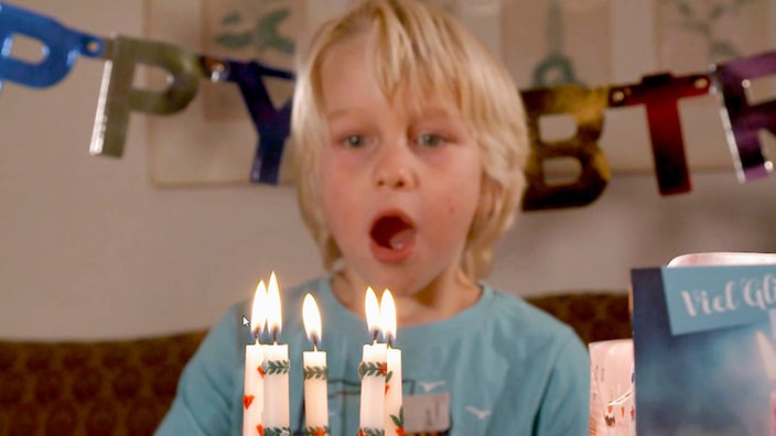 Ein Junge bläst Kerzen auf einem Geburtstagskuchen aus