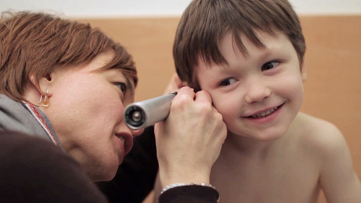 Kinderärztin untersucht das Ohr von einem Jungen