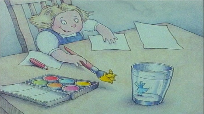 Kind malt Bild  mit Wasserfarben vor ihr steht ein Wasserglas, welches eine kleine blauen Figur beinhaltet