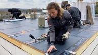 Handwerkerin arbeitet auf dem Dach