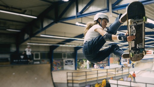 Eine Skaterin vollführt einen Trick in der Halfpipe