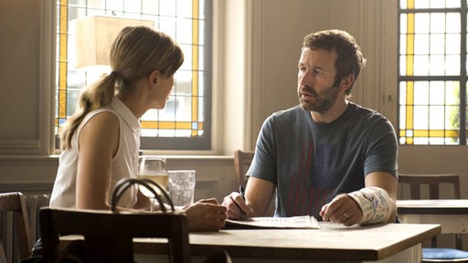 Louise (Rosamund Pike) und Tom (Chris O'Dowd) sitzen an einem Tisch und reden.