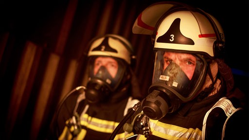 Zwei Feuerwehrmänner mit Atemmasken im Profil