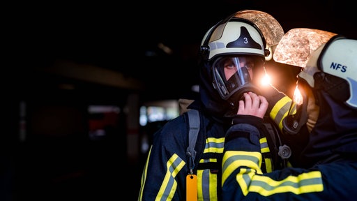 Einem Feuerwehrmann wird die Schutzmaske gecheckt.