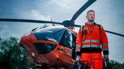 Ein Notarzt steht bei einem Rettungs-Einsatz vor dem Helikopter