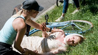 Julia Bergers (Mirka Pigulla, l.) Hilfe ist gefragt, als während ihrer morgendlichen Joggingrunde, eine junge Frau im Brautkleid (Valerie Sophie Körfer, r.) mit dem Fahrrad stürzt.