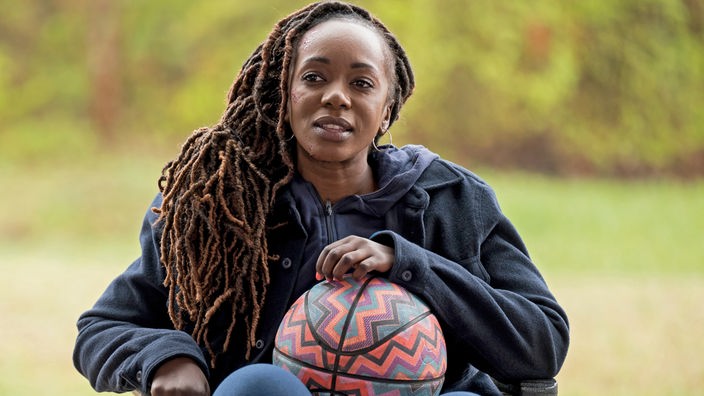 Eine Frau im Rollstuhl mit einem Basketball in den Händen.